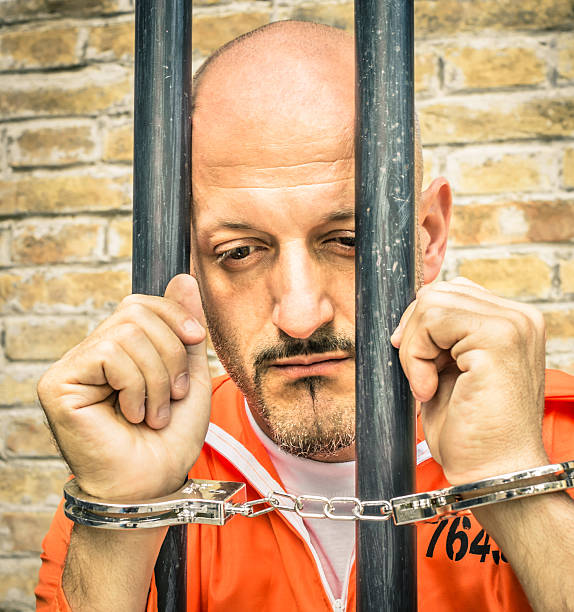 istock Dead Man Walking - Sad Prisoner with Handcuffs behind Bars 186976724