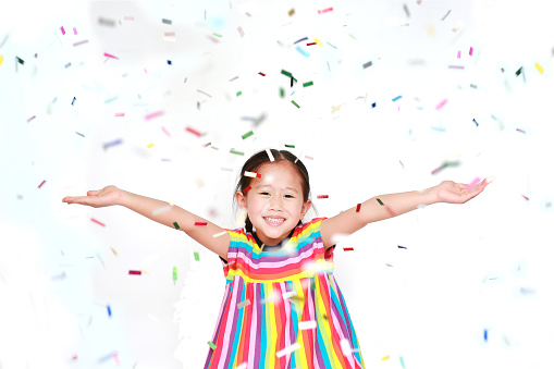 Happy little child girl with colorful confetti on white background. Happy New Year or Congratulation Concept.