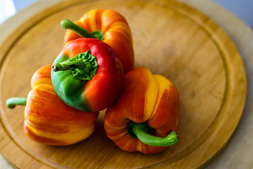 Colorful peppers on the wooden board. Culinary concept.