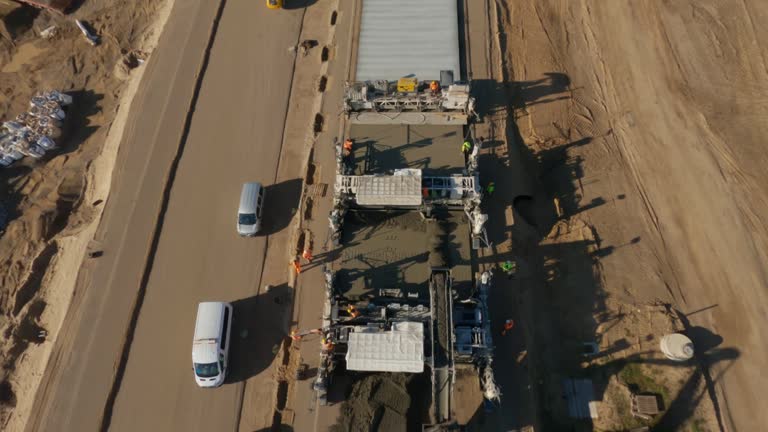 FPV drone flight view construction site of an asphalt highway. Trucks carrying construction materials