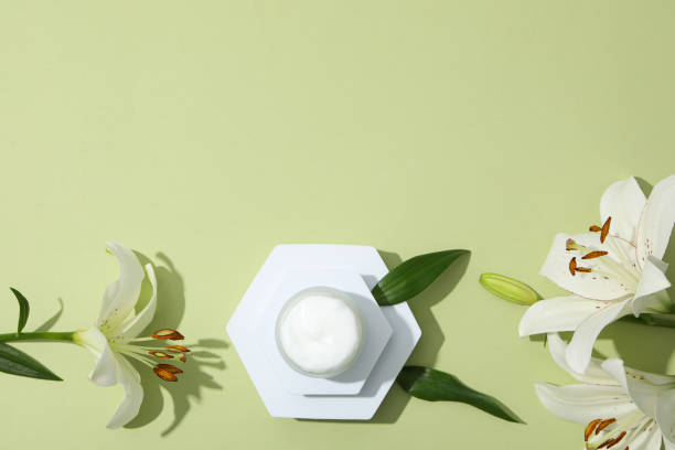 istock Jar with cream and lilies on green background, space for text 1869788073
