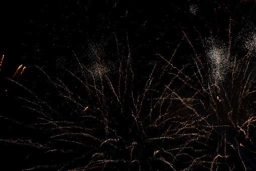 A golden colored fountain firework exploding high in the air like fire, with sparks flying every.