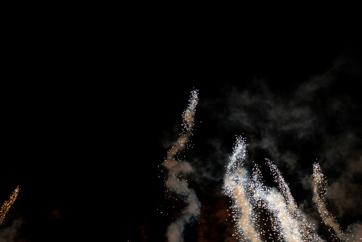 Close-up of two sparklers shaped as 'NUMBER 40' emitting sparks while burning against black background.