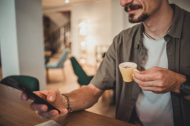 istock A young hipster man in a cafe drinking coffee and using a mobile phone to surf the Internet or correspond on social networks 1869800627