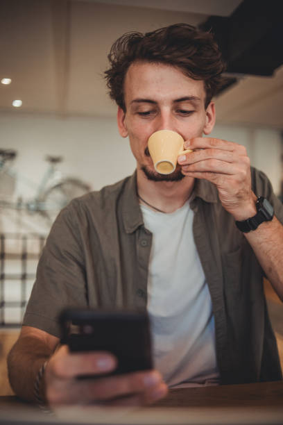 istock A young hipster man in a cafe drinking coffee and using a mobile phone to surf the Internet or correspond on social networks 1869800650
