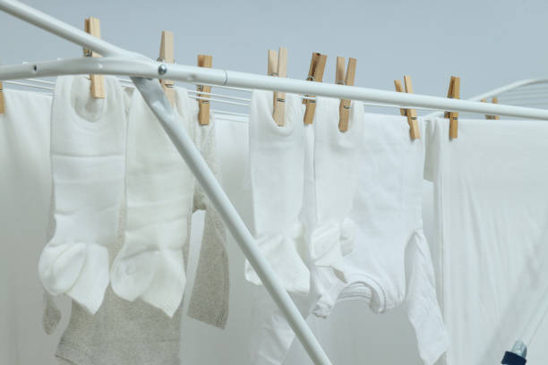 istock Drying rack with socks and clothes against light background 1869809012