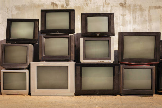istock Retro old TVs pile on floor in front of old wall. Stack television sets with vintage filter effect. 1869809558