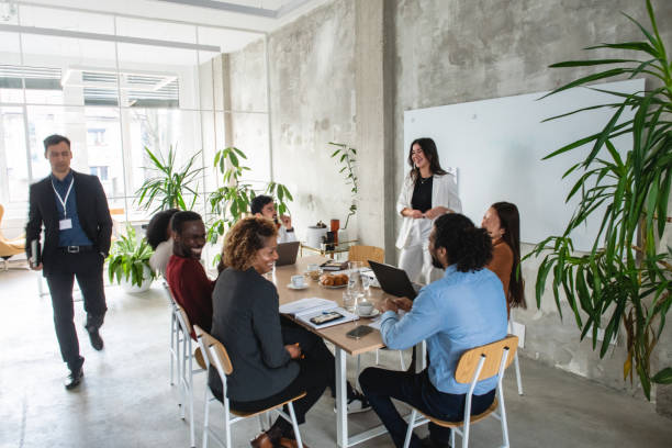 istock Formally Dressed Caucasian Woman Explaining A Project To Multicultural Colleges 1869809589