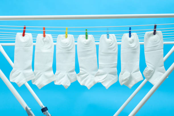 close-up view of clean white socks hanging on clothesline isolated on blue