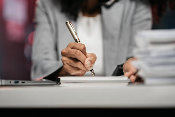istock Business woman using laptop to work and writing on notebook with pen in office with mobile next to laptop. 1869817162