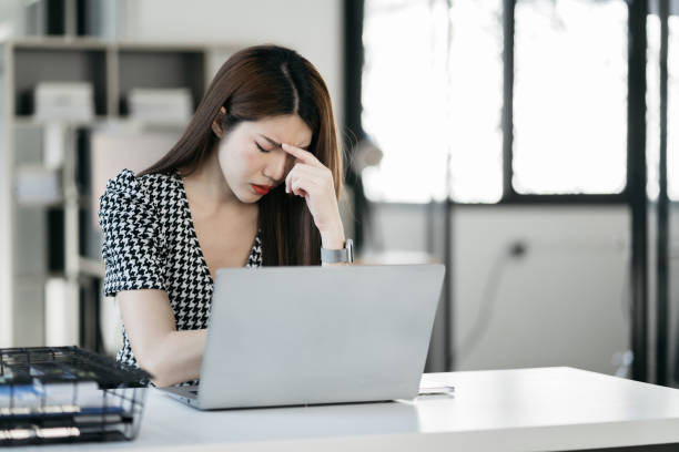 istock Tired asian businesswoman with headache at office, feeling sick at work. 1869817767