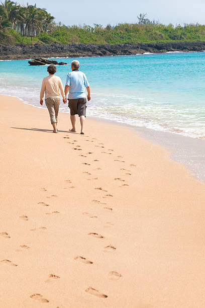 istock happy senior walking on the beach with footprint 186982814
