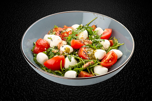 Caprese salad, cherry tomatoes, mozzarella, arugula and pesto sauce. Isolated image