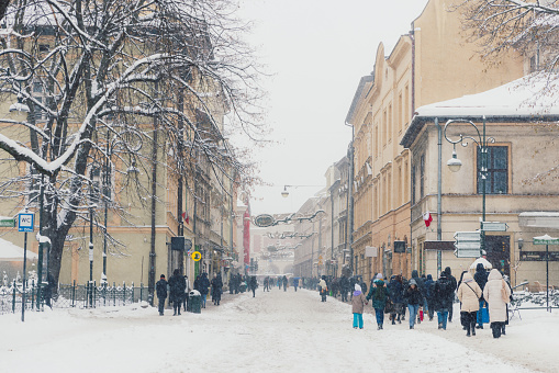 Long Exposure of crowds of tourists on the streets of Old Town of Krakow city during heavy snowing winter weather