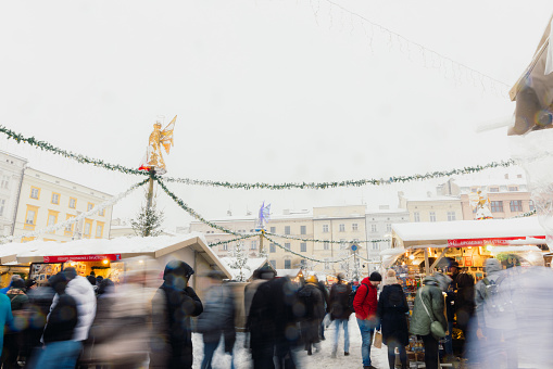Long Exposure of crowds of tourists enjoying the Christmas market at the main square of Krakow city during snowy winter weather