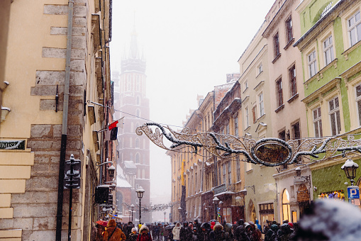 Long exposure of heavy snowfall over the Old Town and authentic buildings decorating by Christmas decorations with crowds of people walking in Krakow, Poland, Europe