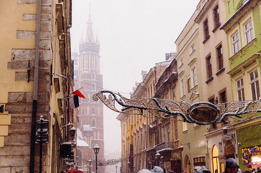 Scenic view of heavy snowfall over the Old Town and authentic buildings decorating by Christmas decorations with crowds of people walking in Krakow, Poland, Europe