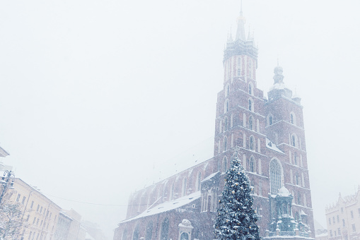 Dramatic view of snow blizzard over the main square of the old town of Krakow city with Christmas decorations and crowds of people