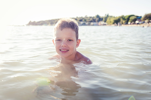 Beautiful boy enjoying sea on a beautiful sunny day. He is happy, smiling, enjoying and laughing.