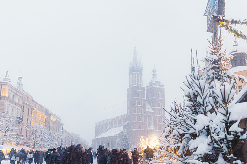 Long exposure dramatic view of snow blizzard over the main square of the old town of Krakow city with Christmas decorations and crowds of people