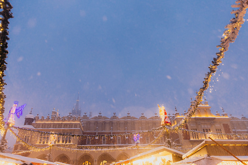 Long exposure of snow blizzard over the main square of the old town of Krakow city with Christmas decorations and crowds of people during twilight