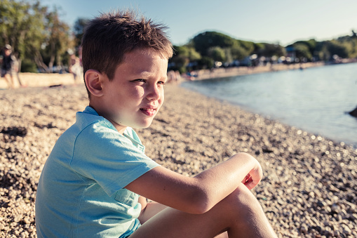 Cropped shot of a cute boy relaxing in sand on the beach at sunset.