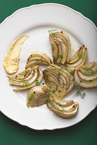 Roasted fennel with herbs and red pepper, a wonderful side dish full of minerals and vitamins on a rich green background