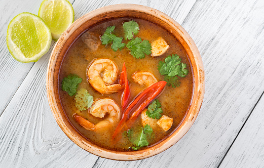 Bowl of tom yum soup on wooden background