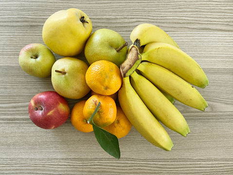 Table top view group of fresh fruits on wood background. Banana, apple, tangerine, pear, quince