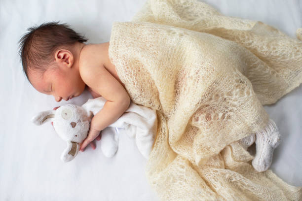 istock Newborn baby with a soft toy bunny on a white background. 1869908817