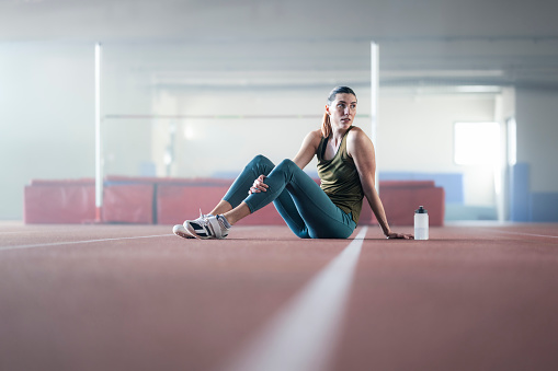 Athlete young woman sitting in sports hall.