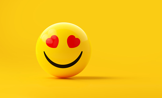 Yellow sphere textured with happy face emoji on yellow background. Horizontal composition.