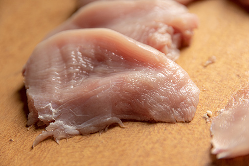 Turkey breast on wooden chopping board, close-up
