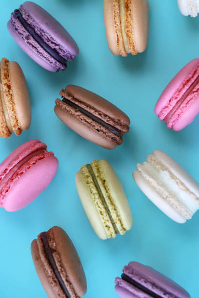 istock Full frame image of macarons on edge, multi coloured macarons filled with flavoured butter cream, chocolate, vanilla, blueberry, pistachio, orange, strawberry flavoured meringues, blue background, elevated view 1869927854