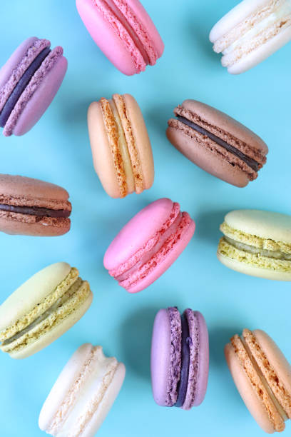 istock Full frame image of macarons on edge, multi coloured macarons filled with flavoured butter cream, chocolate, vanilla, blueberry, pistachio, orange, strawberry flavoured meringues, blue background, elevated view 1869927870