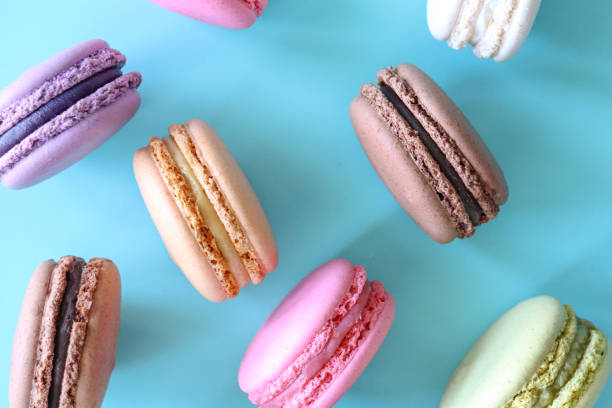 istock Full frame image of macarons on edge, multi coloured macarons filled with flavoured butter cream, chocolate, vanilla, blueberry, pistachio, orange, strawberry flavoured meringues, blue background, elevated view 1869928404