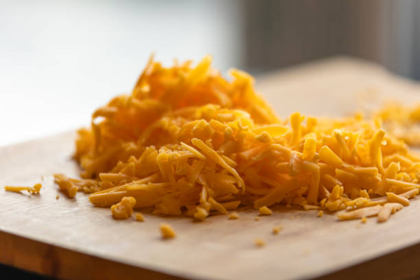 istock Shredded Cheddar Cheese on Wooden Board Close-Up 1869937473