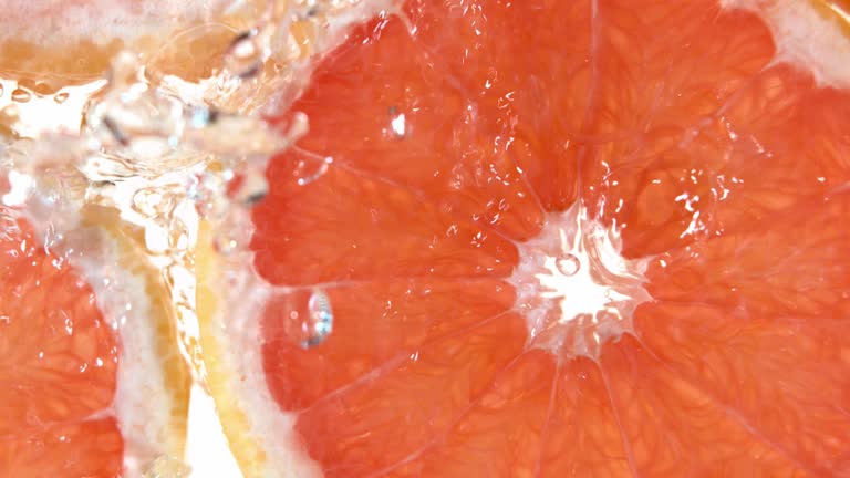 Super slow motion of grapefruit slices with water splashing.