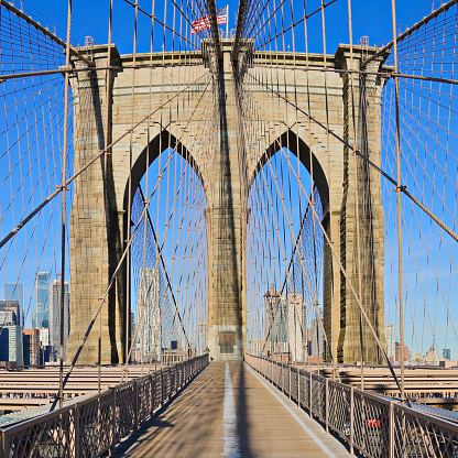 Daytime view of the Brooklyn bridge and the pointed arches of its suspension tower.