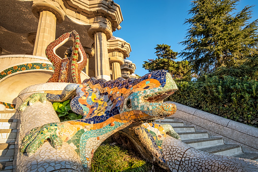 December 16, 2023 - Barcelona, Spain: Early in the morning at Parc Guell with Lizard Fountain of Antoni Gaudi Barcelona in front of the steps in the park, Spain. A mosaic dragon which has become the symbol of the city.