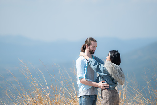 Young couple in love on the top of the mountain with holding a miniature windmill