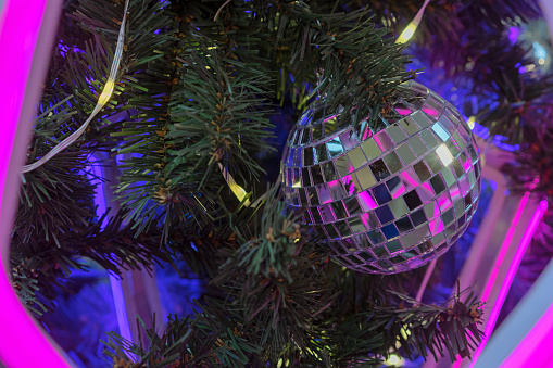 Disco Mirror Ball in neon light on a Christmas tree.