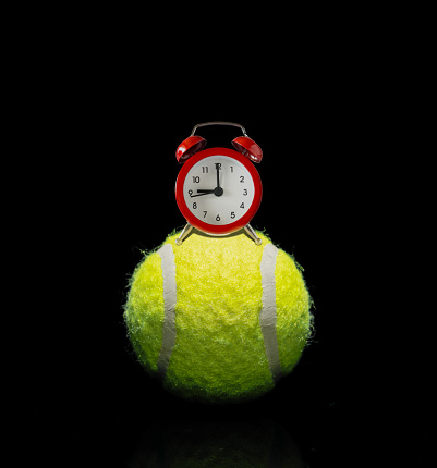 Retro analog alarm clock on top of a tennis ball
