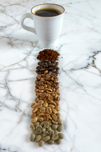 sStages of coffee roasting with roasted coffee beans and coffee drink on marble table top