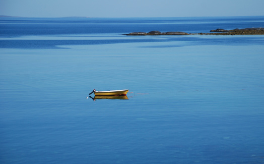 Lonely yellow boat in the blue sea, Barents sea, Norway