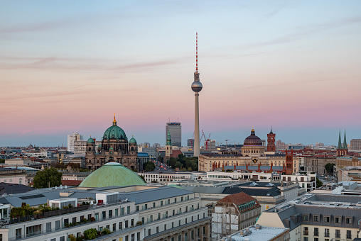 A picture of some Berlin landmarks as seen from afar, at sunset, such as the Berliner Fernsehturm, the Berlin Cathedral and the Berlin Palace.