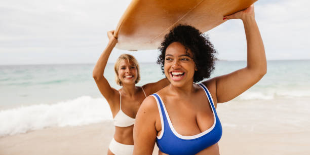 istock Surfers having fun together, carrying a surfboard and smiling on the beach 1869990808