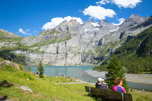 Oeschinen Lake, Switzerland–Aug 3,2023: travelers enjoying the Alps sunshine  with snow caped mountain in the background