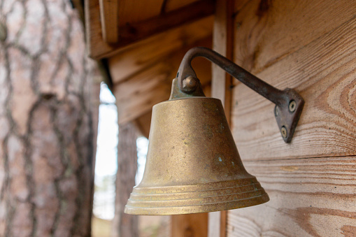 A bronze bell hangs on a wooden wall