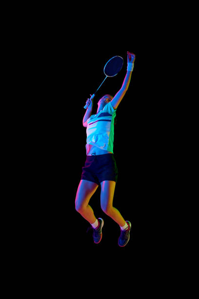 istock Professional female badminton player training in motion against black background in neon light. 1870036891